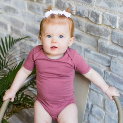 baby on chair wearing mauve color lucky friend onesies